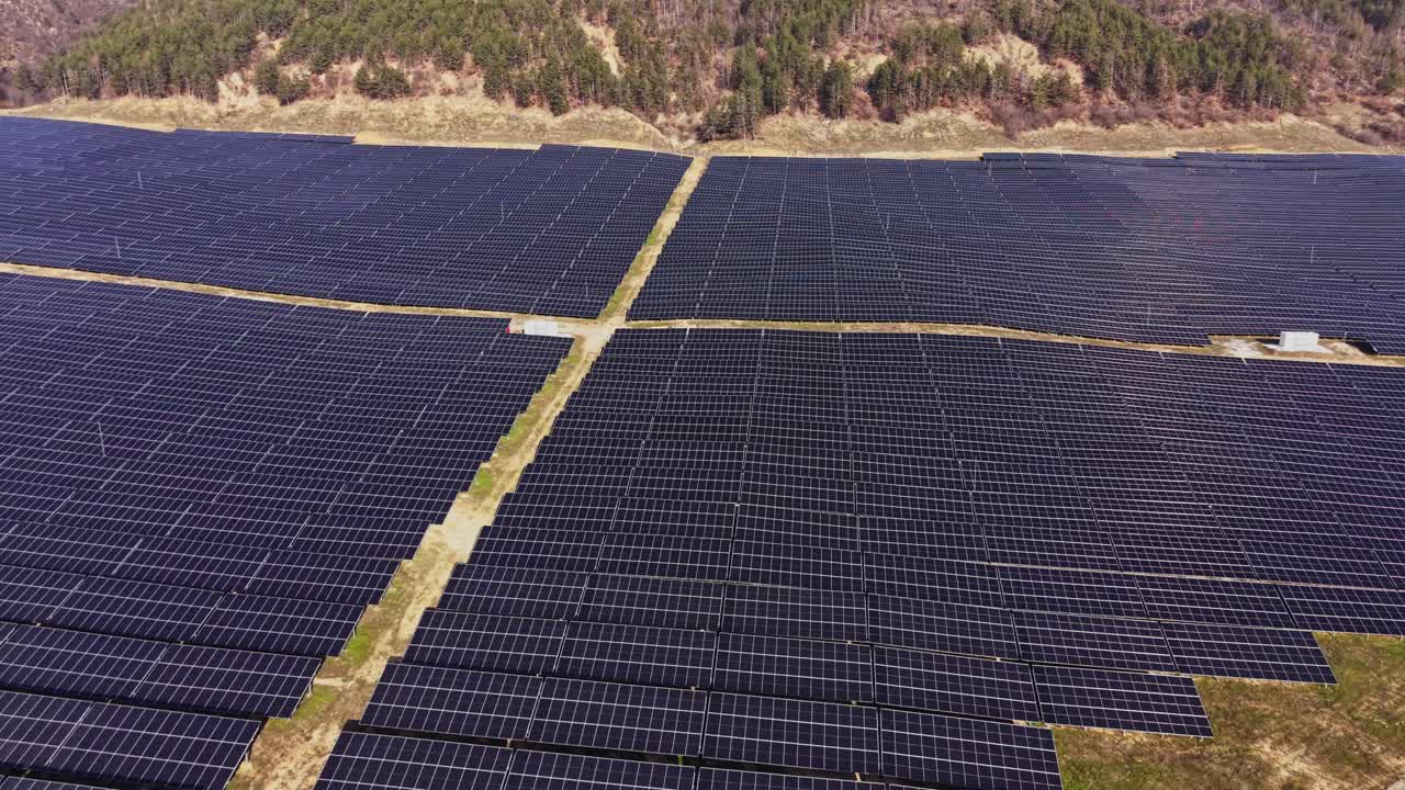 Solpaneler dækker et stort område i et grønt landskab i løbet af dagen