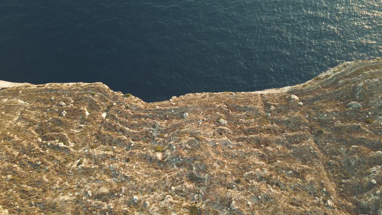 vista aérea cinematográfica mirando hacia abajo un acantilado vertical sobre un mar pacífico abriendo lentamente la perspectiva hacia el horizonte, imágenes de drones
