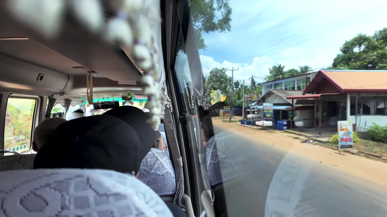 View from inside a tour bus traveling through Sri Lanka, capturing reflections in the window and the vibrant landscape. slow motion