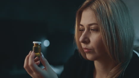 suspicting woman holds pill bottle on blurred background