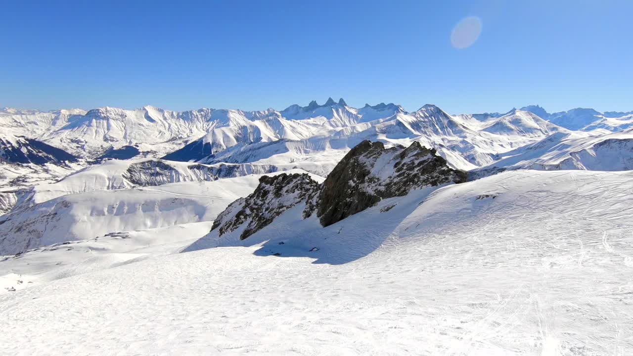 A droneshot of a snowy mountain landscape in the French Alps in winter, sunny weather