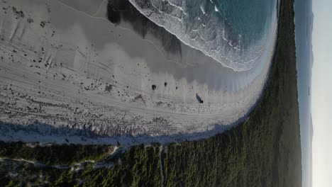 Disparo-De-Un-Dron-Siguiendo-El-Coche-En-La-Playa-De-Arena-De-La-Playa-De-Wylie-Bay-Al-Atardecer