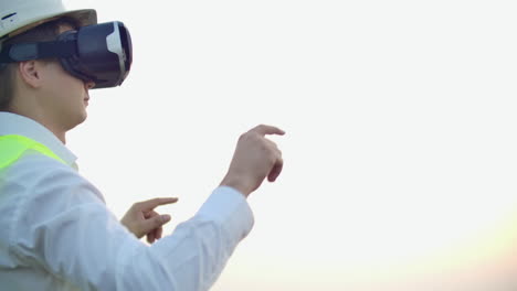 portrait of a male crane operator operating a construction site using virtual reality glasses. construction manager manages the progress and plan of buildings using gestures at sunset