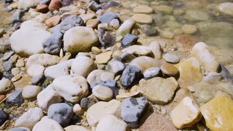 slow motion shot of water rushing through the rocks on the ground on a bright sunny day