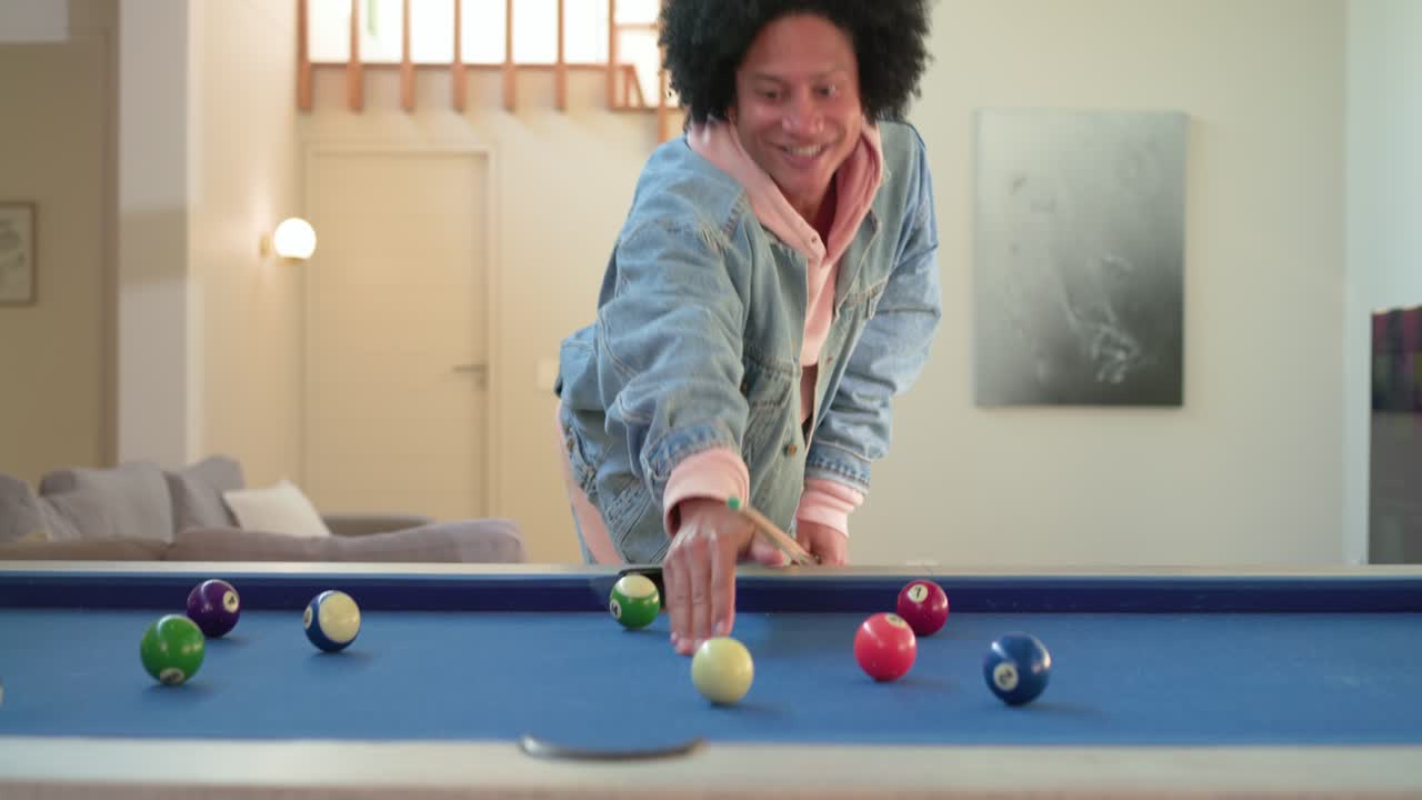 African American man entering game room chalking cue and shooting balls on felt table practicing