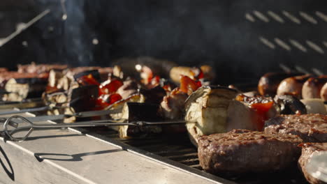 Barbacoa-Con-Hamburguesas-De-Ternera-Y-Brochetas-De-Verduras-Con-Luz-Nocturna-Y-Humo-Saliendo-Del-Carbón-Caliente-Debajo