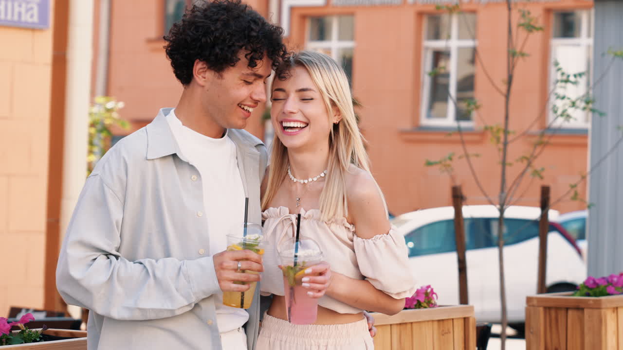 una pareja joven disfrutando de bebidas al aire libre.