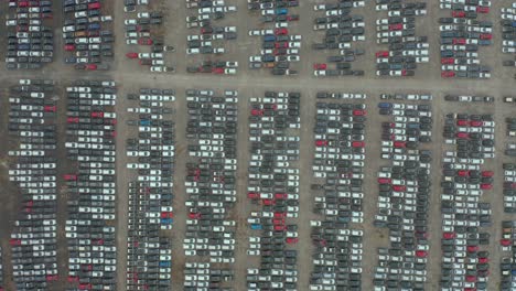 above cenital shot of brand new cars parking lot, automobile factory top down drone view, zoom in of a group of vehicles