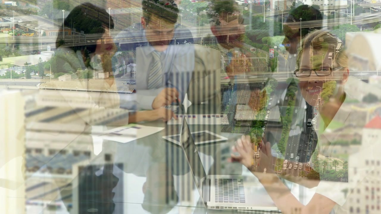 Business team leaning over docs, typing, pointing while aerial overlay showing traffic for planning