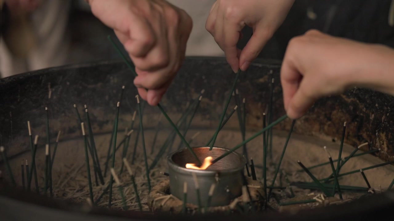 Vista de cerca de personas encendiendo varitas de incienso en un templo japonés en Japón, mostrando manos, incienso encendido, humo y un ritual religioso tradicional.