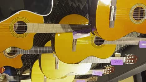 a large selection of acoustic guitars in the music store. stringed musical instruments. vertical video