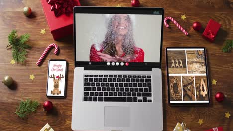 Caucasian-woman-in-santa-costume-on-video-call-on-laptop,-with-smartphone,-tablet-and-decorations