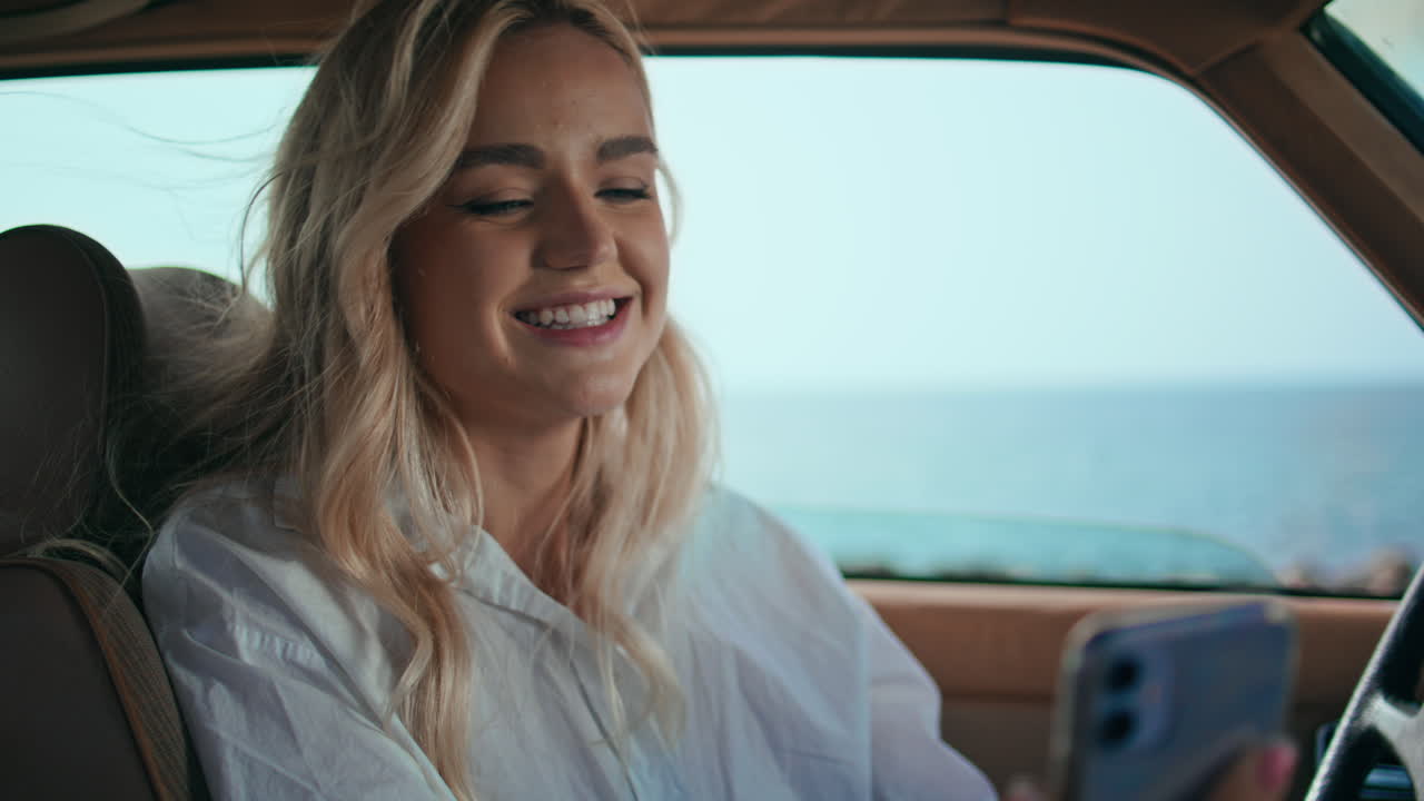 una mujer sonriente llamando por teléfono inteligente en un automóvil de cerca. una chica agitando la mano.