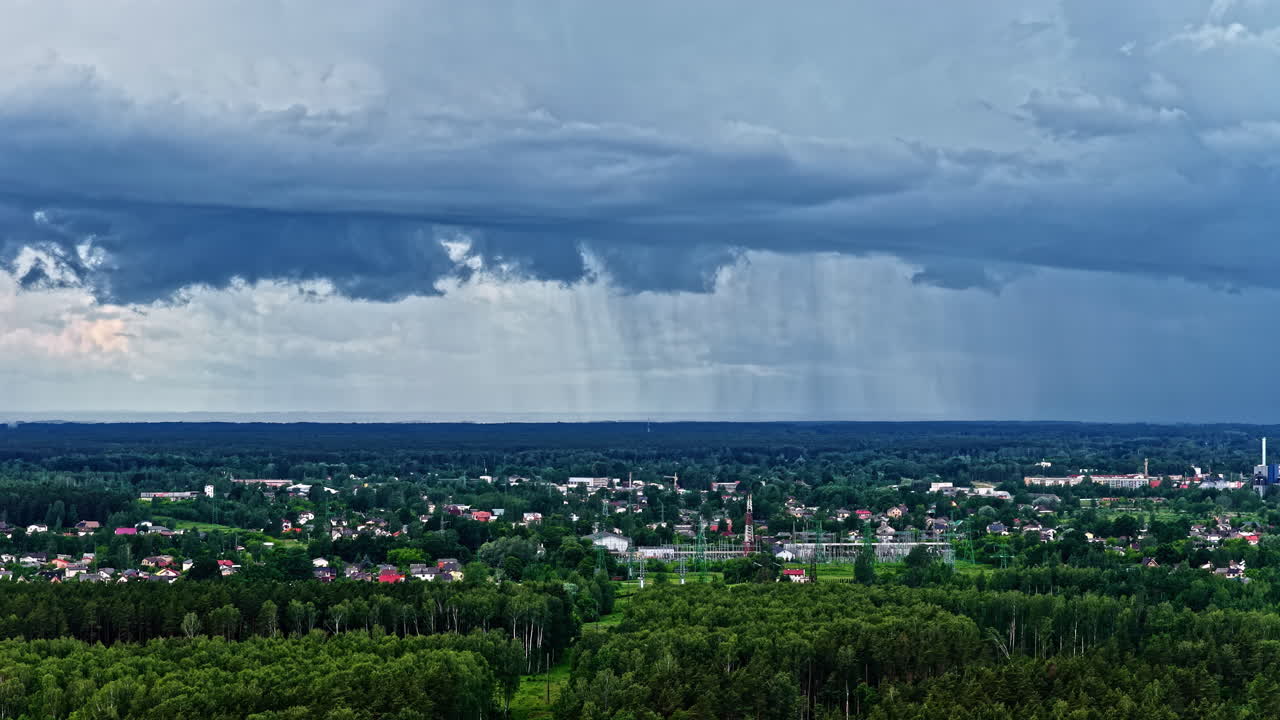 Rain falling from a cloud in the distance in a village with a lot of trees