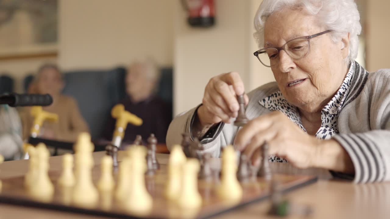 Two senior friends playing chess board game in a geriatric