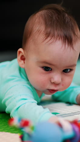 sweetest child in blue outfit tries to reach his toy. funny toddler takes a toy and shakes it. blurred background. vertical video