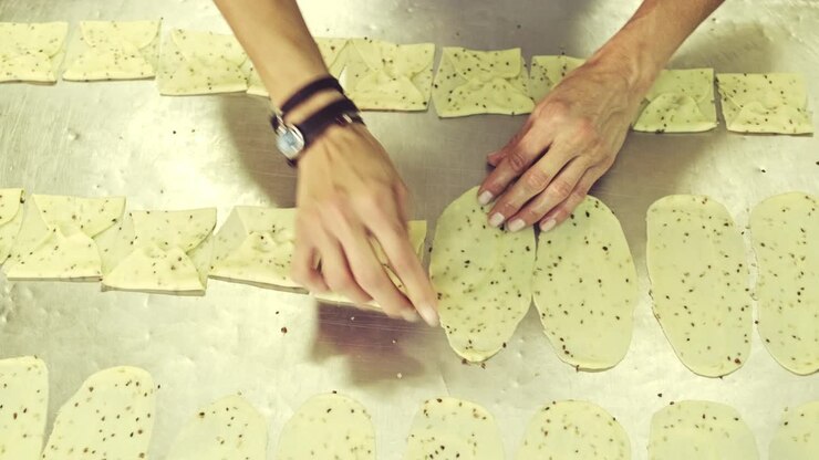 Crop baker shaping flatten dough in kitchen