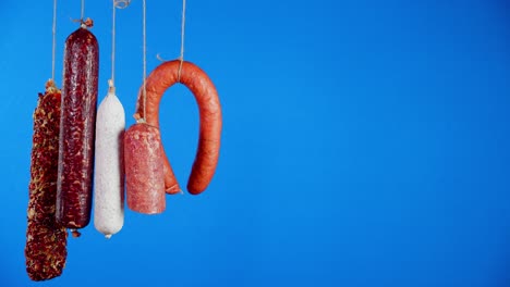 different types of sticks of salami hanging on the rope.