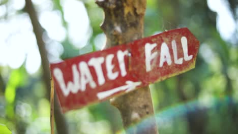 Slow-Motion-shot-of-a-sign-coming-into-focus-that-says-WATERFALL-with-an-arrow-pointing-down-the-trail