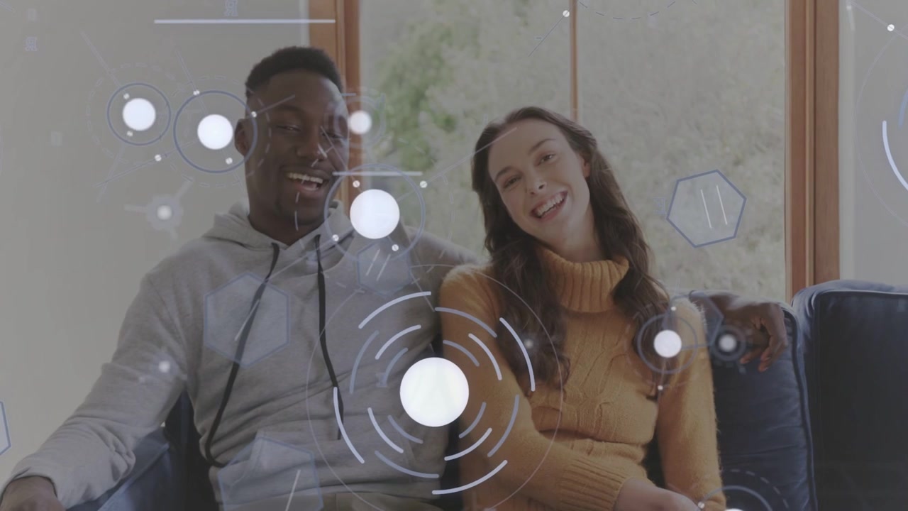 Pair exchanging looks, man draping arm on sofa, tech hex overlaying faces, building rapport