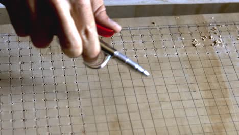 using compressed air to blow away the saw dust from a grid of drilled holes in plywood