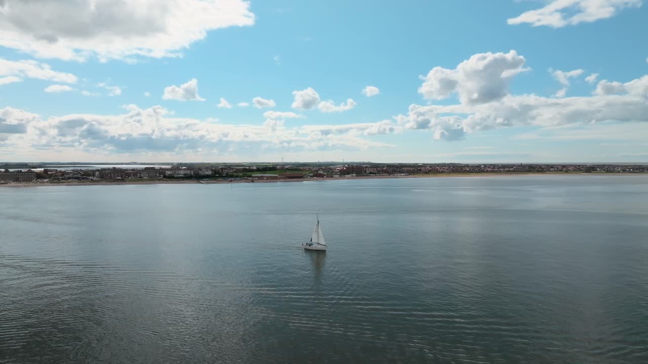 Yacht On Calm Water At River Wyre Estuary With Coastline Of Fleetwood In Background And Clouds Reflecting In Still Water. Lancashire, UK