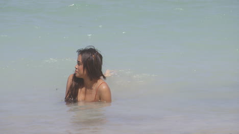 latin brunette girl bathing in exotic beach seashore waves in summertime heat