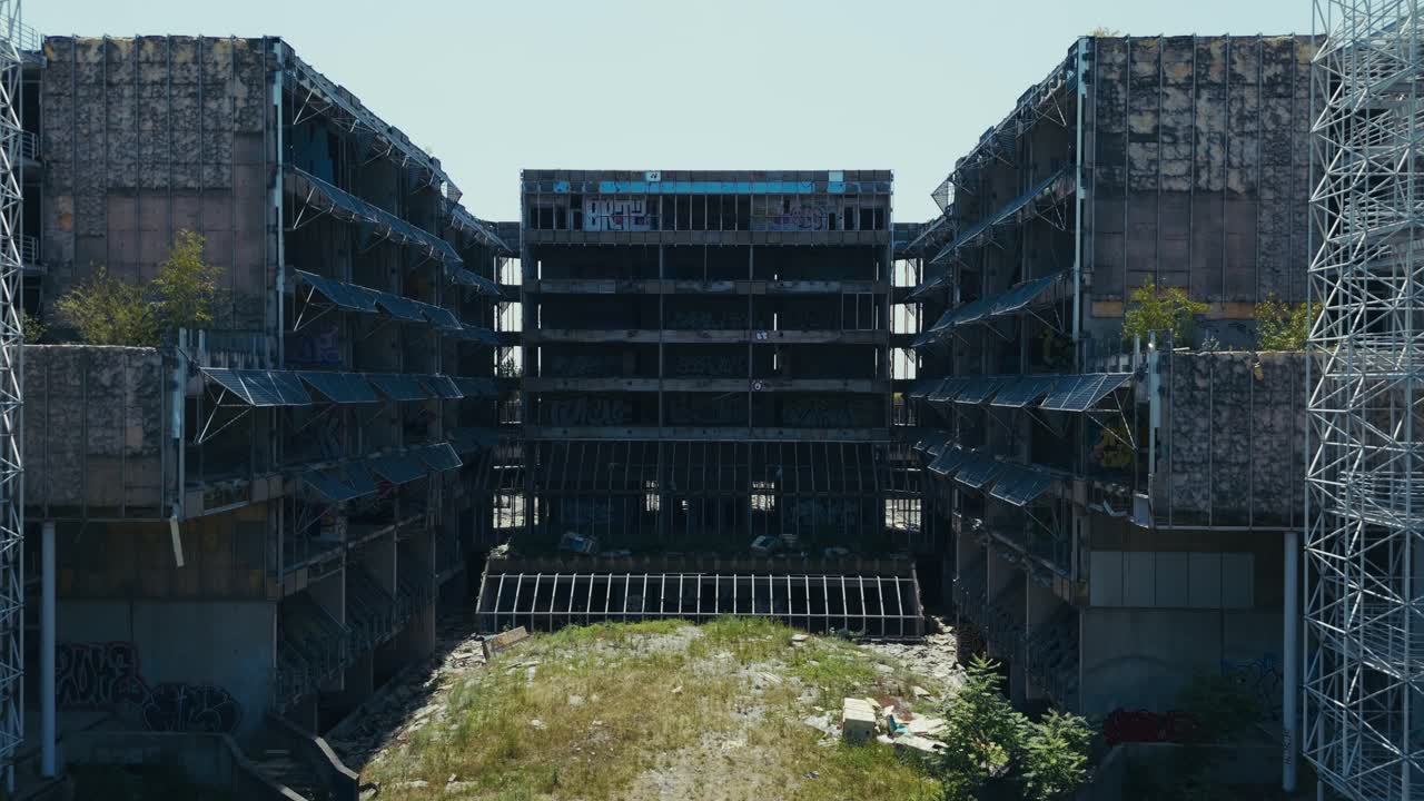 inner courtyard of derelict hospital framed by exposed floors and graffiti