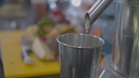 Nahaufnahme-Des-Rackfokus-Eines-Entsafters,-Der-Saft-In-Eine-Tasse-Tropft