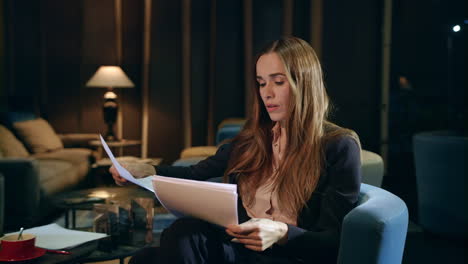 serious businesswoman working with documents in hotel lobby at evening