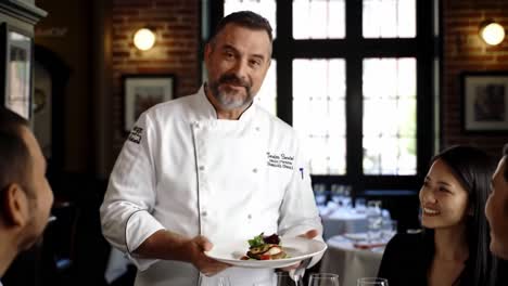 chef presenting artfully crafted dish to diners in elegant restaurant setting, highlighting culinary skill and fine dining experience for guests