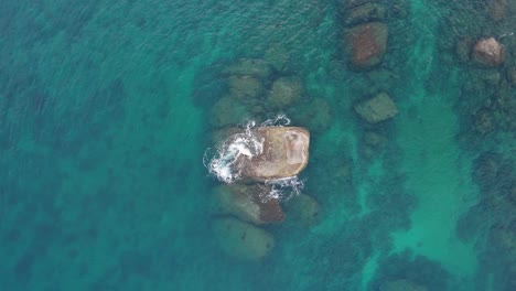 Espectacular-Vuelo-De-Drones-De-4k-Lejos-De-Una-Piedra-Rodeada-Por-Las-Olas-En-El-Océano-En-Phuket,-Tailandia,-Cerca-De-Hermosas-Palmeras-Y-árboles-Verdes,-Olas-Rompiendo-En-La-Orilla