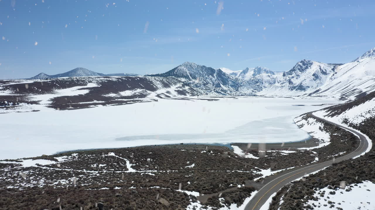 camino rural con majestuosa vista de la cordillera nevada durante las nevadas, vista aérea descendente