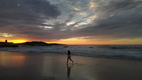 chica con un vestido blanco corre en la playa mientras sale el sol