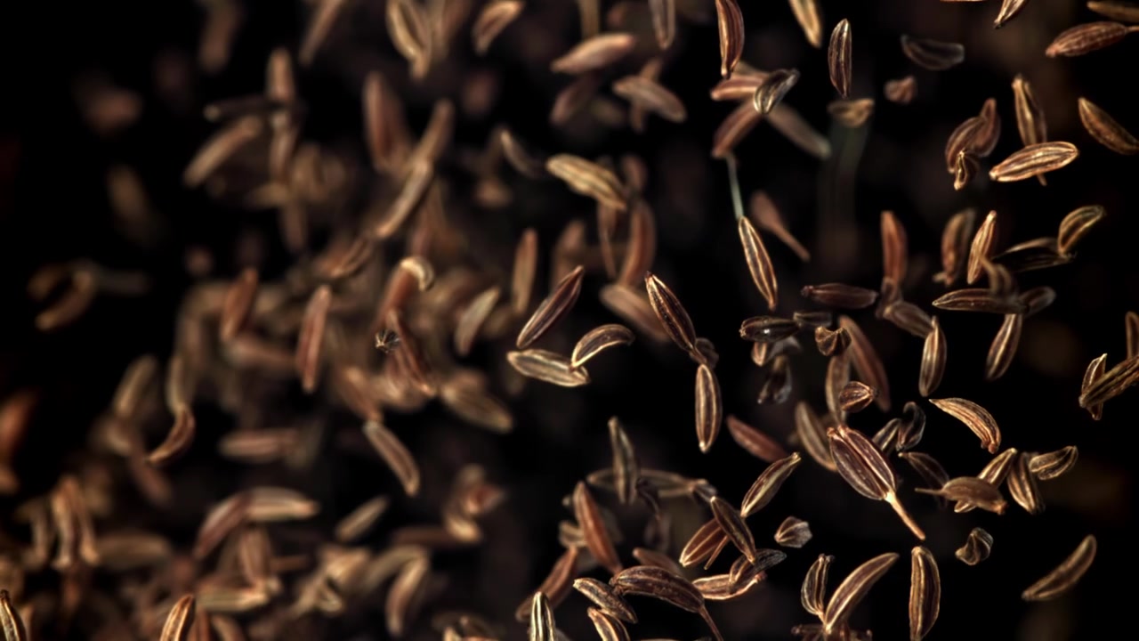 Cumin Seeds Falling in Slow Motion on Black Background