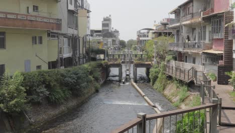 a river passing through a canal with 3-story buildings on both sides in a small village in southern taiwan - wide