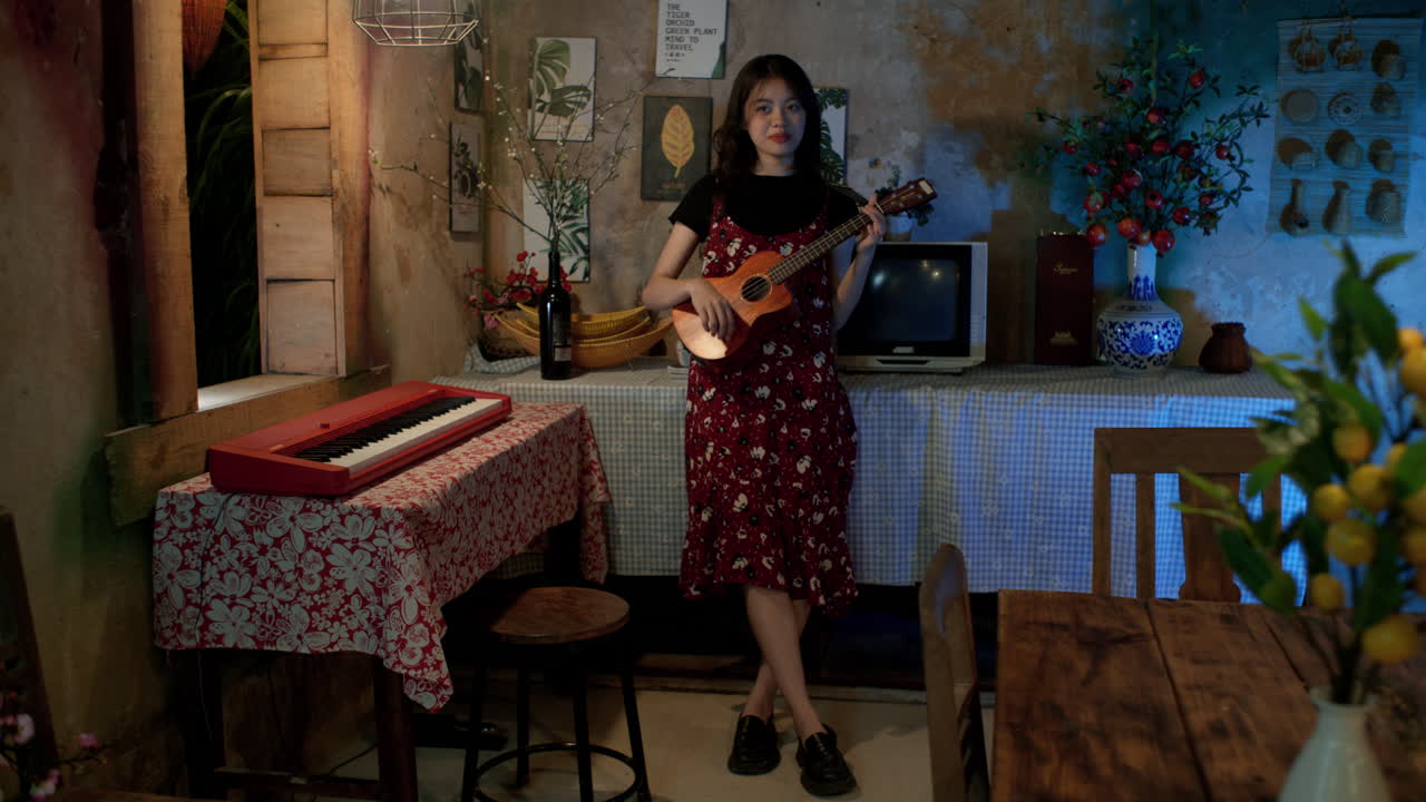 mujer asiática linda con vestido floral cantando y tocando el ukelele en casa, decoración e interiores vintage