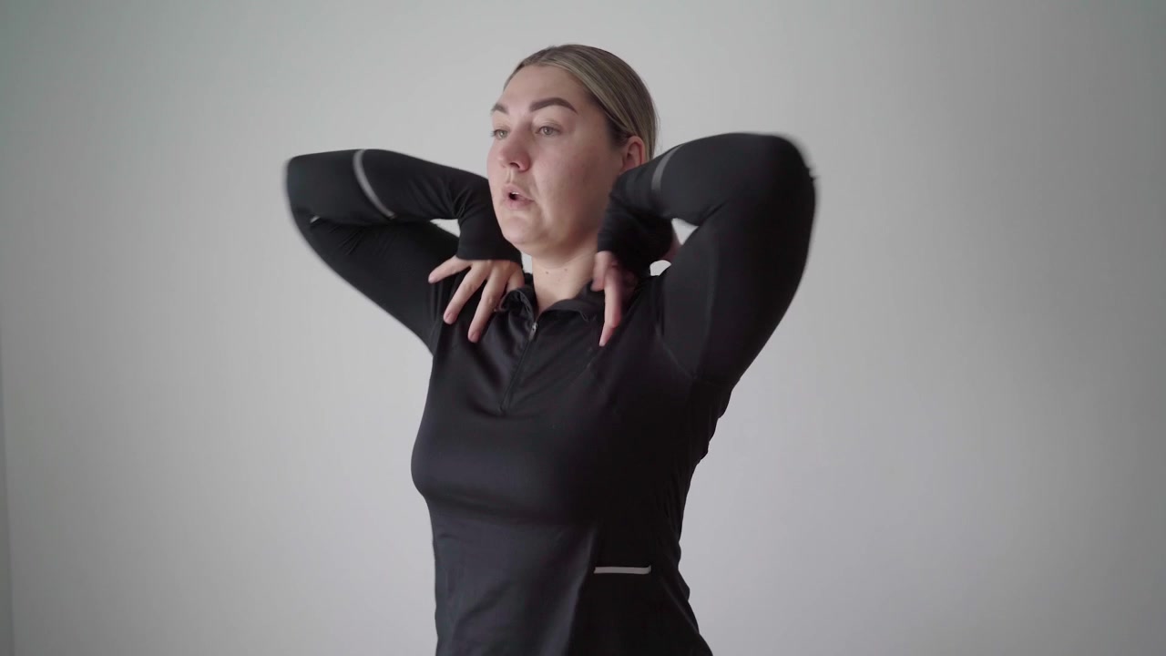 Deportista concentrado realiza encogimientos de hombros dinámicos de pie con las manos en la parte superior del pecho para relajar el cuello y la parte superior de la espalda antes de un entrenamiento