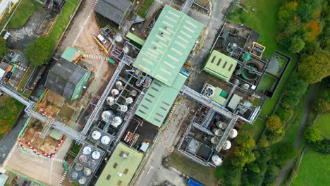 Aerial-video-nears-a-UK-chemical-plant,-displaying-pipelines,-metal-frameworks,-cooling-towers,-and-chemical-storage