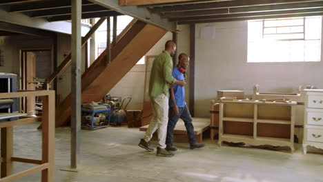 descending stairs african american coworkers in workshop using tablet and inspecting frame piece
