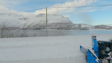 static shot of a male with a snow blower walking into the frame on a calm day in northern europe, removing snow