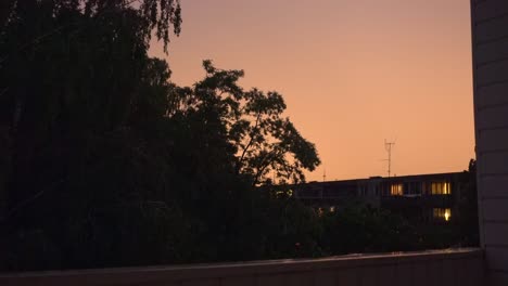 lightning bolt strike over urban city area surrounded by trees. flash of thunderbolt light on a rainy dark night. climate change.