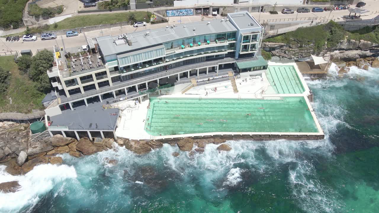 호주 뉴사우스웨일스 주 본다이 - 파도가 부서지는 본다이 해변의 수영장에서 관광객들이 수영을 합니다.