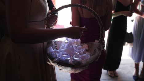 wicker basket with white ribbons held by guest during wedding entrance