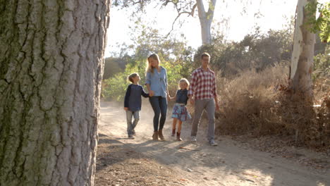 young white family walking on a path in sunlight, front view