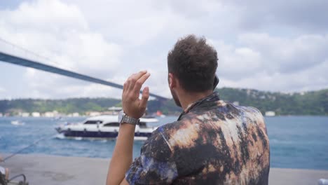 young man talking on the phone by the sea.