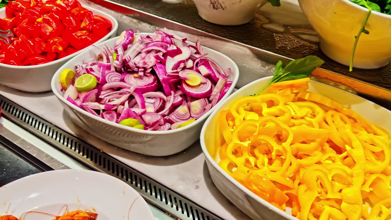 Person scooping salad from buffet of colorful vegetables and fresh toppings inside restaurant, daylight scene