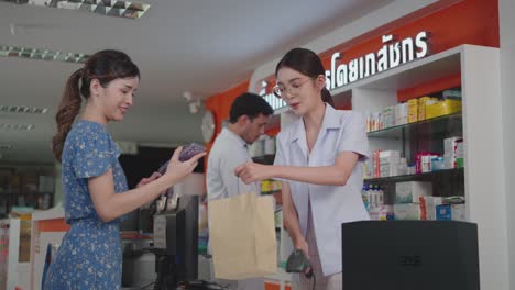 woman pharmacist scanning a barcode at a smartphone for contactless payment.