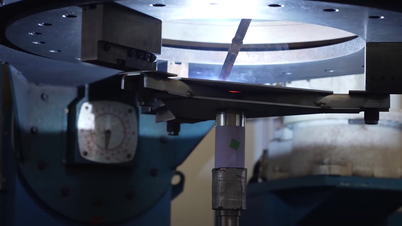 Automated welding station with rotary table and robotic arm performing precision welds inside safety enclosure