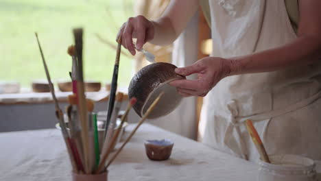 woman painting a ceramic bowl in a pottery studio